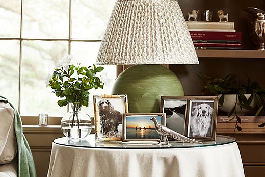 A pleated patterned lampshade, a skirted table, flowers, and framed photos of dogs: the epitome of English cottage style. Photo by Frank Tribble.
